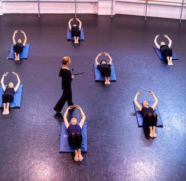 A picture of Andrea teaching dance conditioning to a group of students